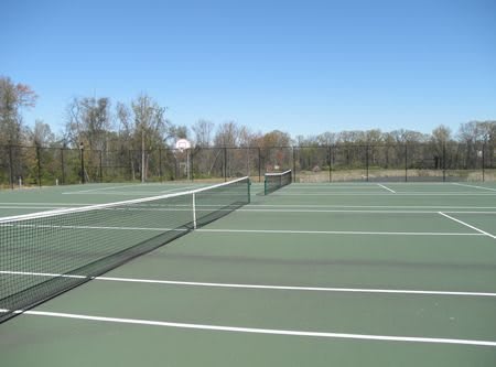 An empty outdoor tennis court under a clear blue sky.