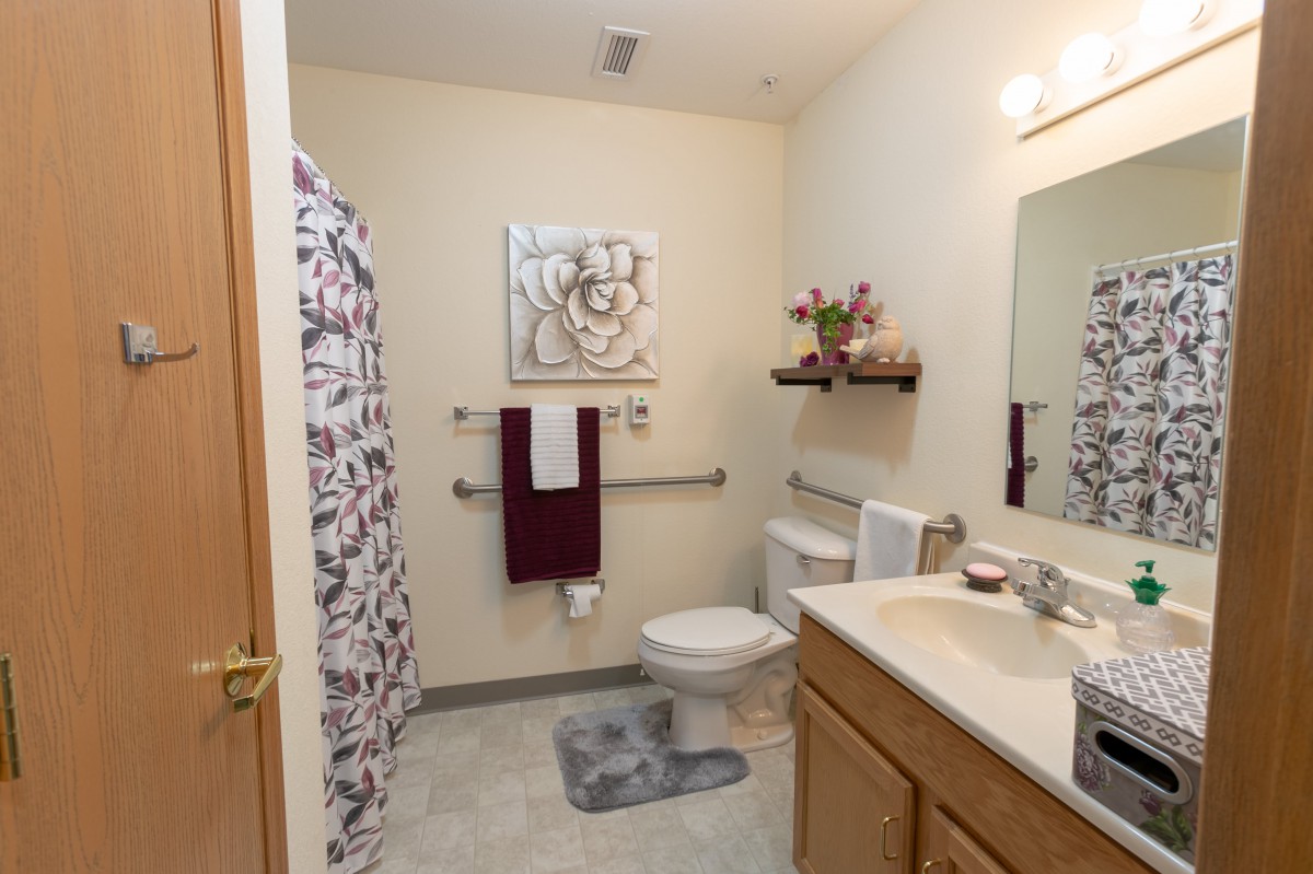 A clean and well-organized bathroom with a sink, toilet, and shower area.