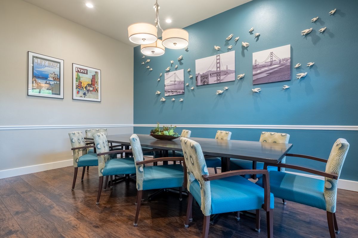 A modern dining room with blue accent walls, stylish chairs, and contemporary wall art.