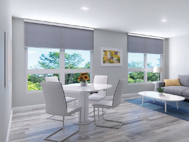 A modern and minimalist living and dining area featuring white furniture, large windows, and an abundance of natural light.
