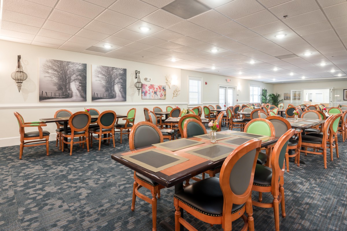 A well-lit dining room with neatly arranged tables and chairs, featuring elegant decor.