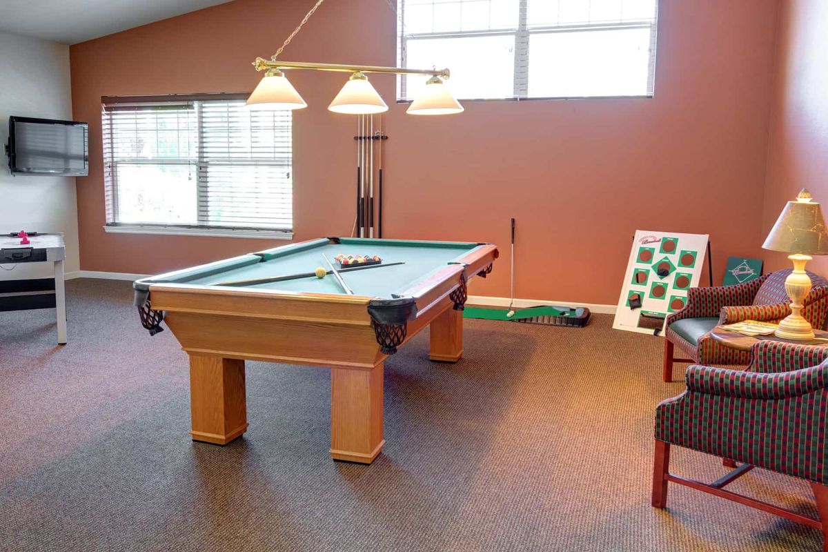 A well-lit game room featuring a pool table and seating area.