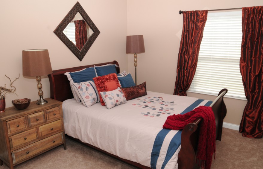 A cozy bedroom with a neatly made bed, decorative pillows, and warm lighting.