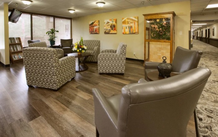 A cozy waiting room with comfortable armchairs, wooden flooring, and decorative art on the walls.