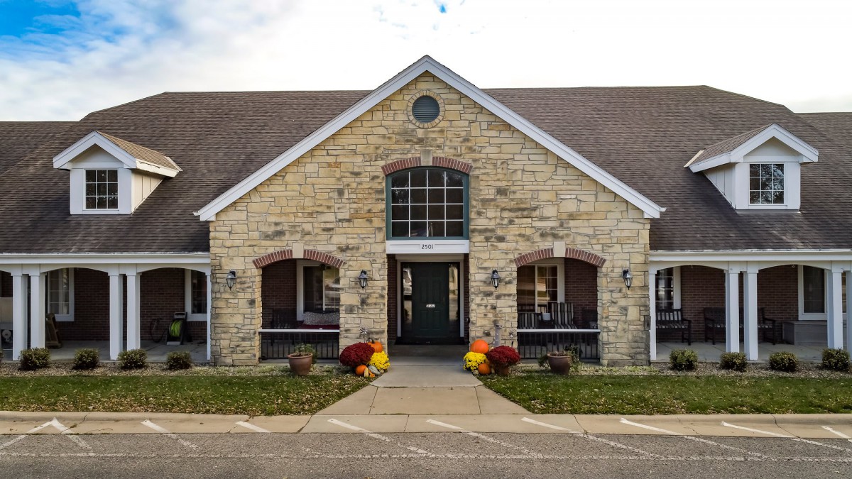 A stone building with large windows and a welcoming entrance adorned with colorful flowers.