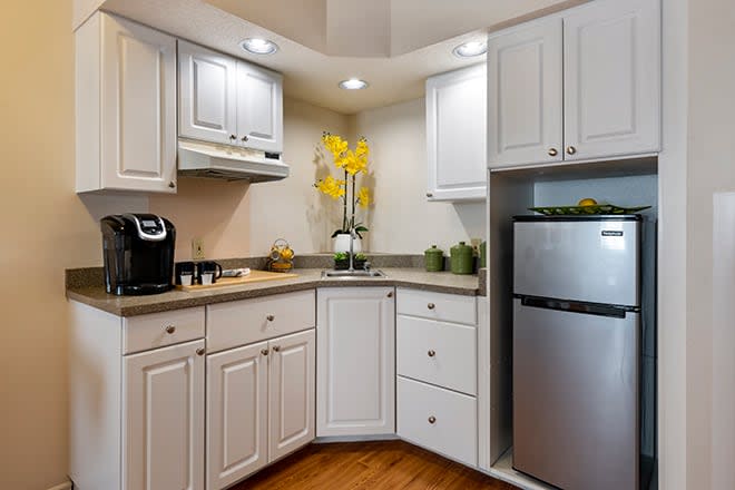 A modern kitchen with white cabinets and a stainless steel fridge.