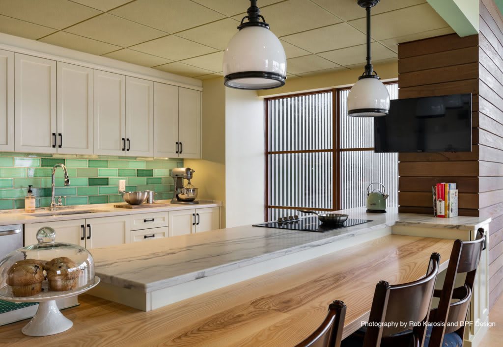 A modern kitchen interior with a large island, pendant lights, and a colorful backsplash.