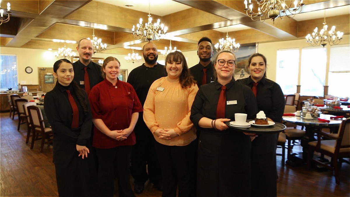 A group of restaurant staff posing together inside the dining area.