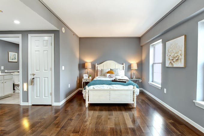 A well-lit bedroom with a comfortable bed, hardwood floors, and stylish decor.