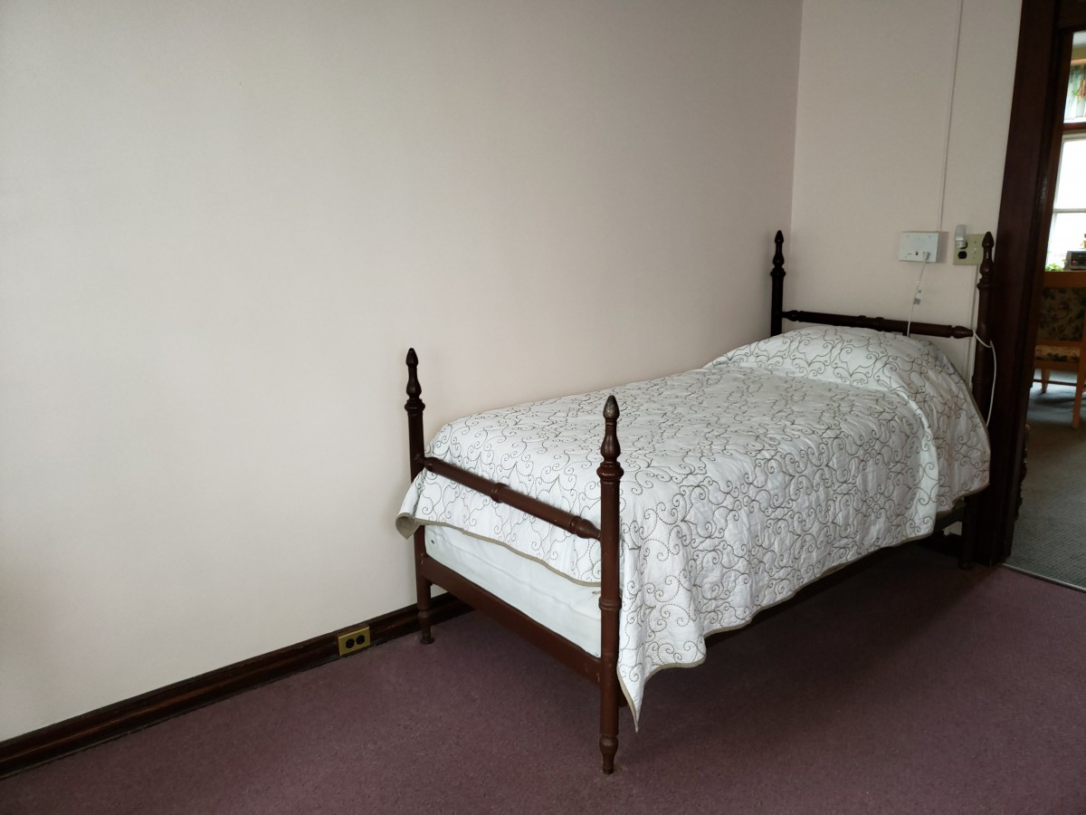 A minimalist bedroom featuring a single bed with a light-patterned cover.