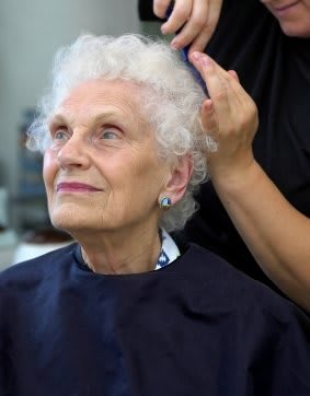 An elderly woman getting her hair styled at a salon.