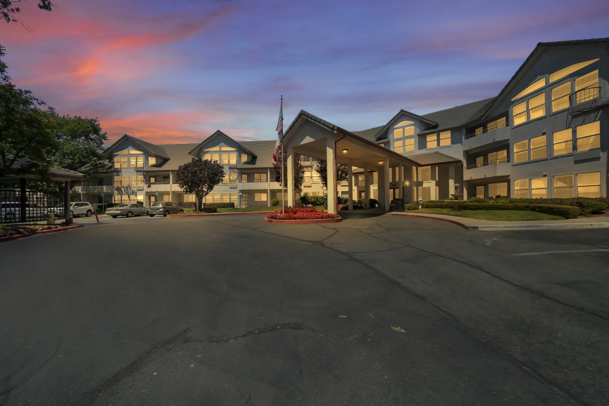 A large building with a welcoming entrance, seen during twilight with a colorful sunset sky.