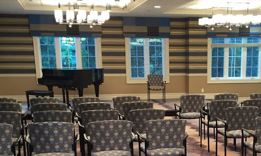 A spacious and inviting interior featuring upholstered chairs, a grand piano, and large windows allowing natural light.