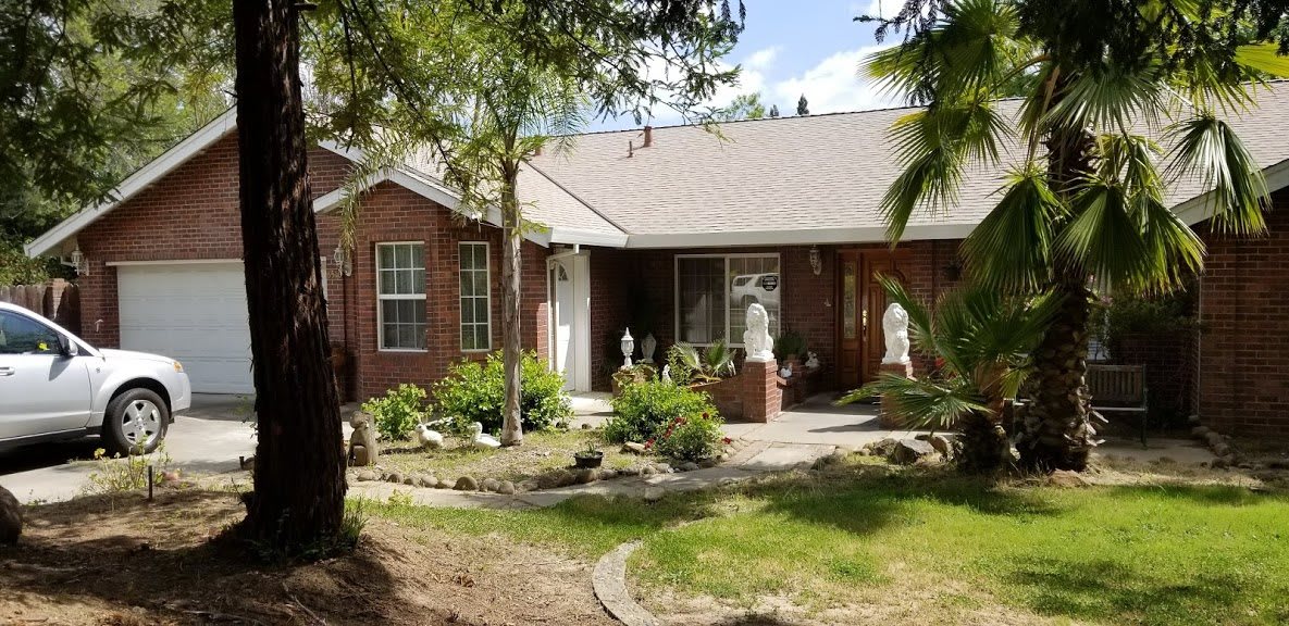 A brick house with a well-maintained front yard featuring statues and greenery.