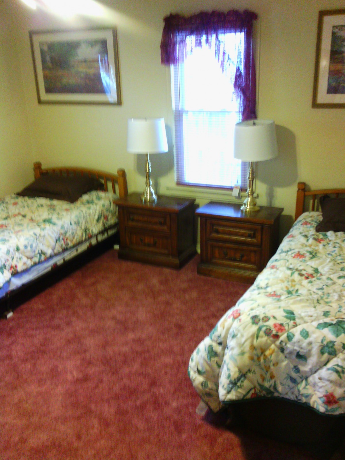 A cozy bedroom with twin beds, floral bedding, and a soft carpeted floor.