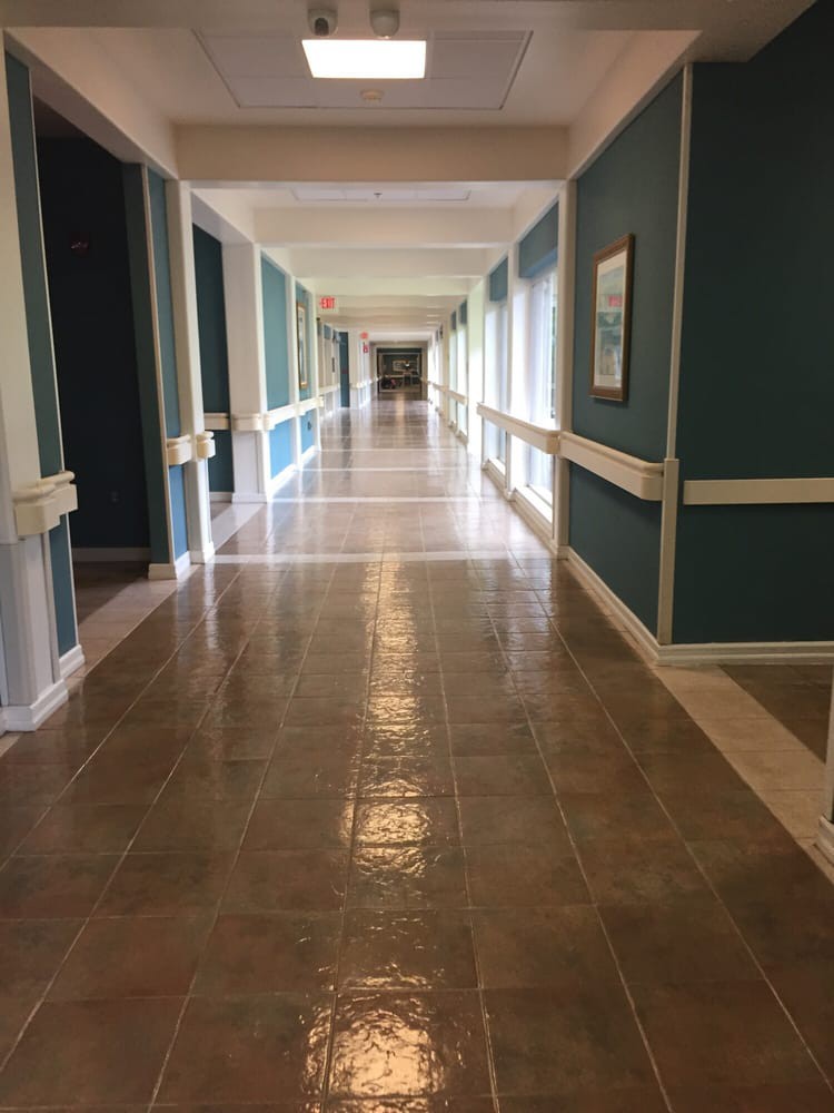 A long, empty hallway with teal walls and shiny floors.