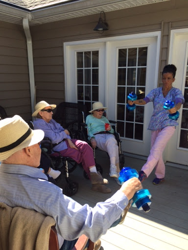 A caregiver engaging with seniors outside on a sunny day.
