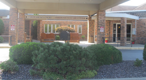 A view of a brick building with benches and greenery in the foreground.