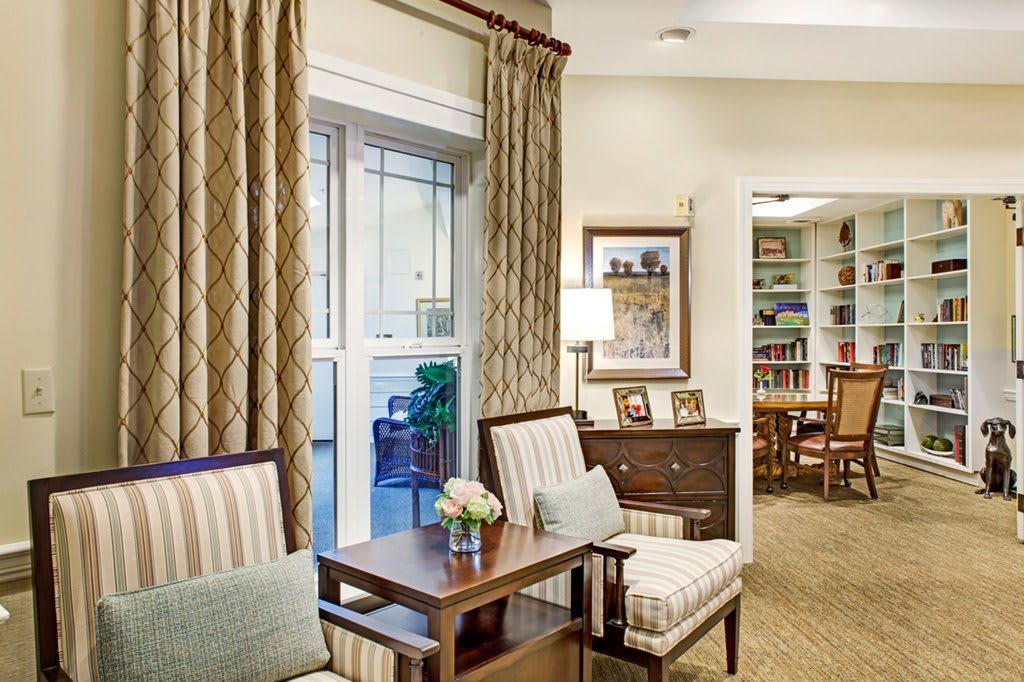 A cozy living room with armchairs, a side table, and a bookshelf.