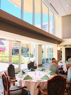 A beautifully lit restaurant interior featuring elegantly set tables and chairs with large windows providing ample natural light.