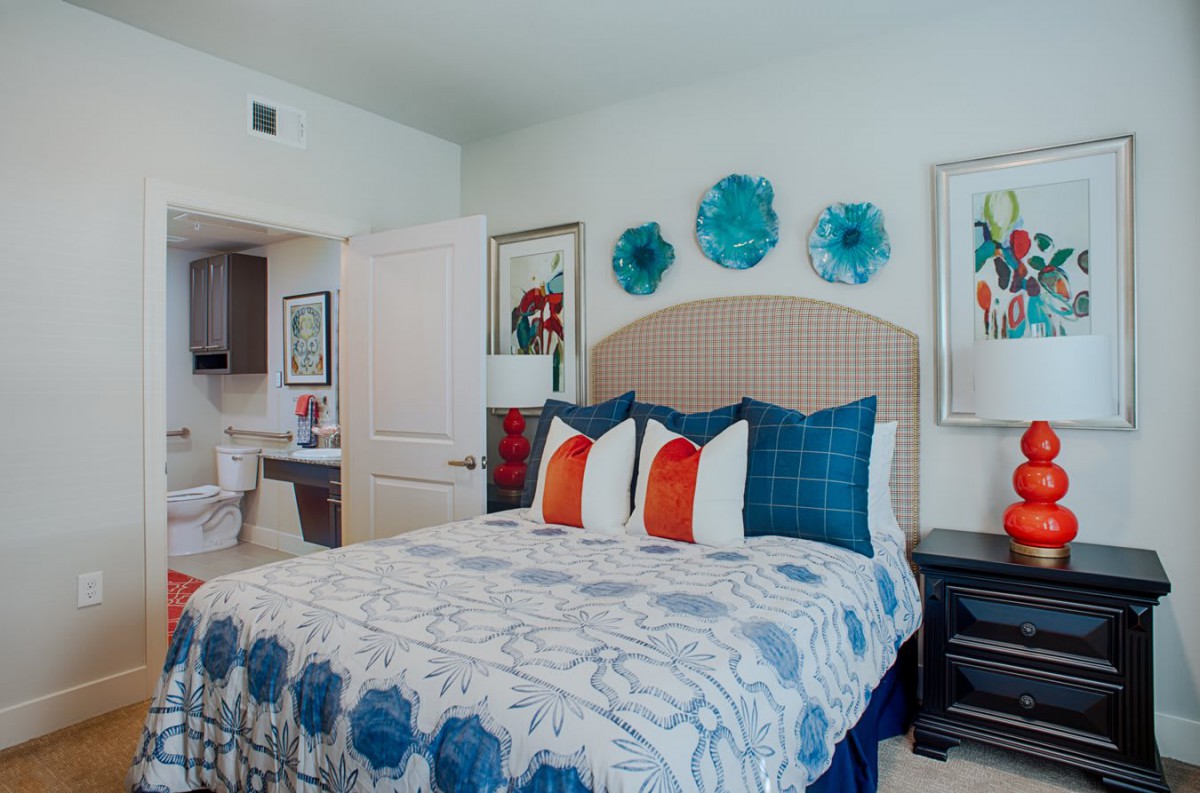 A stylish bedroom with vibrant wall art and colorful pillows.