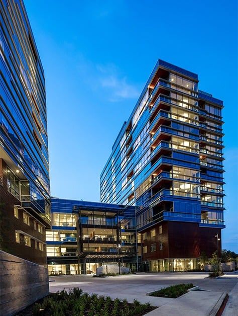 A modern office building with illuminated glass facades during the evening.