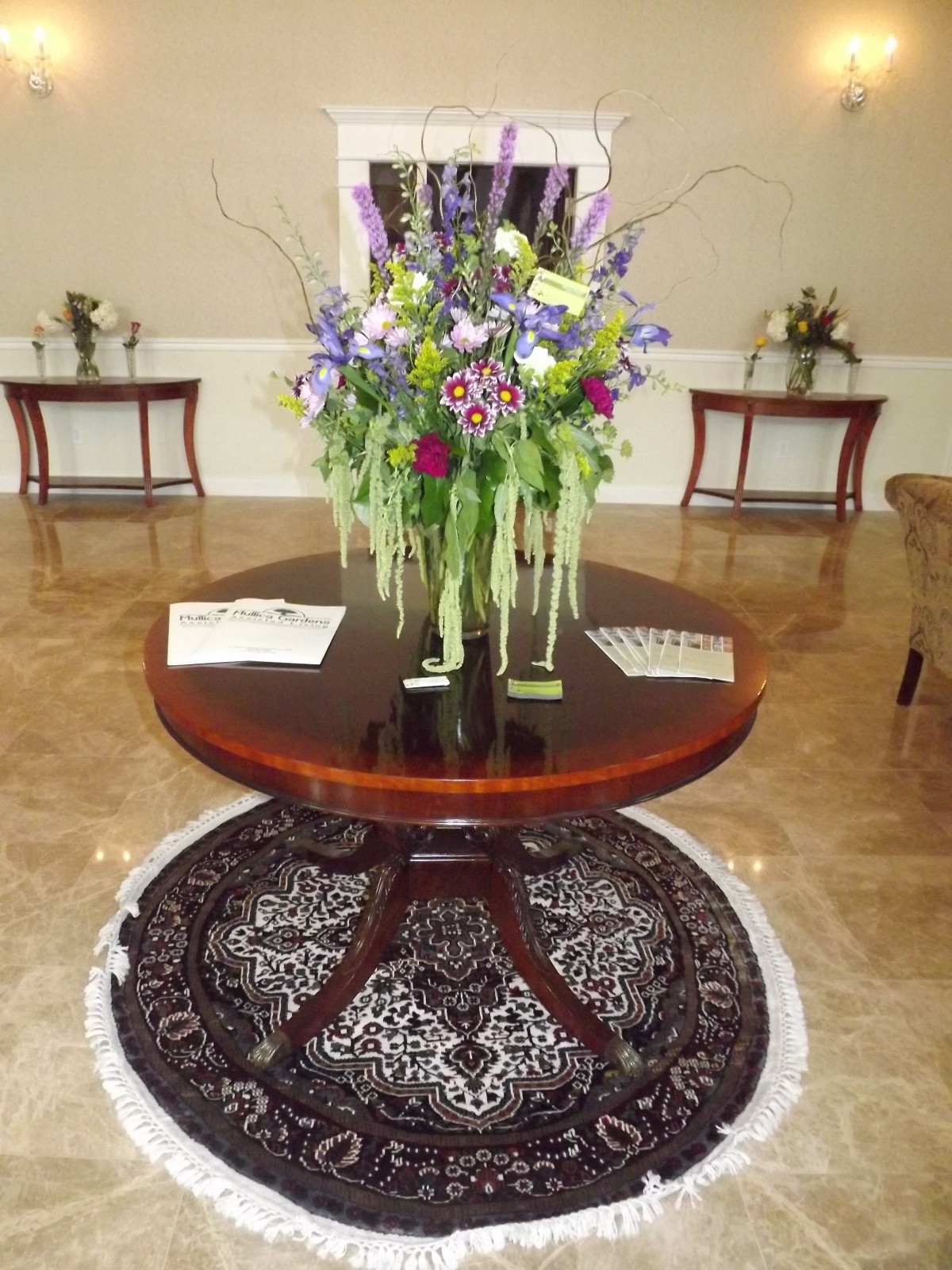A beautifully arranged floral centerpiece on a round wooden table in a lobby setting.