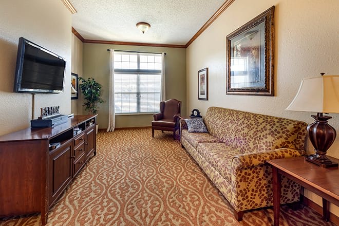 A cozy living room with a patterned carpet, sofa, and television.