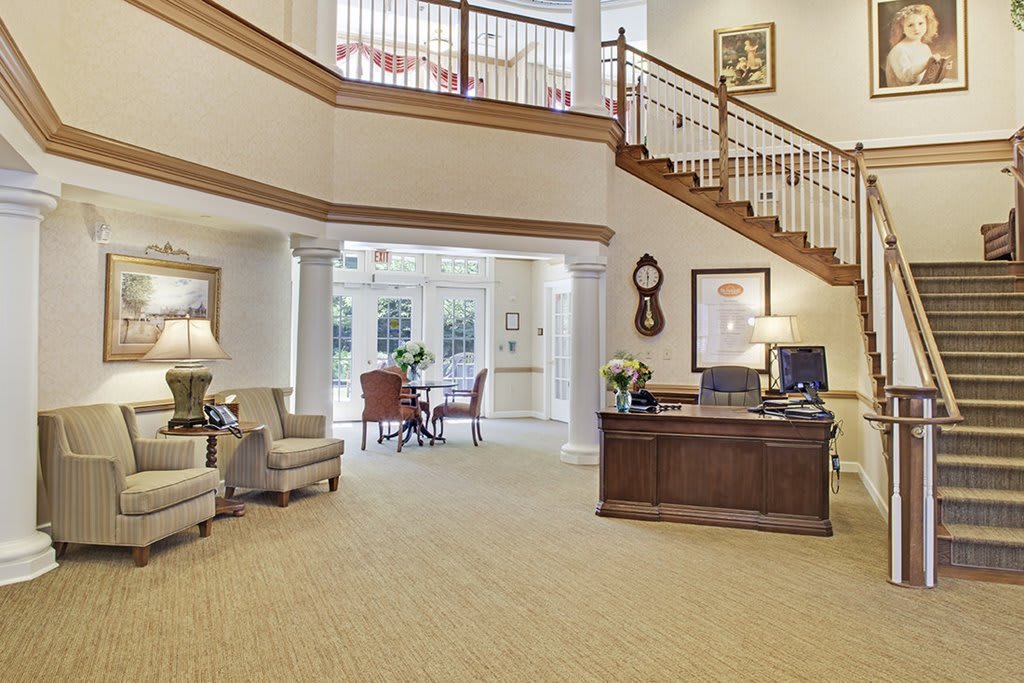 Spacious lobby area with a reception desk and furniture, featuring an open staircase.