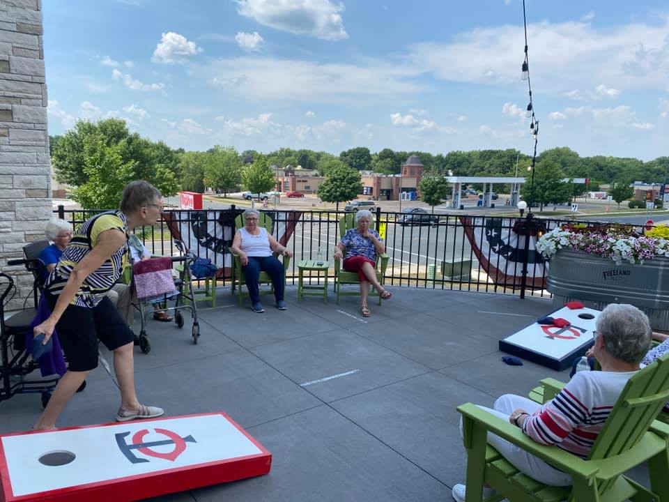 A group of people enjoying a game of cornhole on a sunny patio.