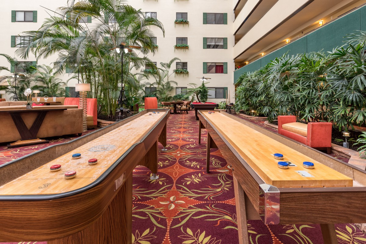 Indoor recreation area with shuffleboard tables and seating.