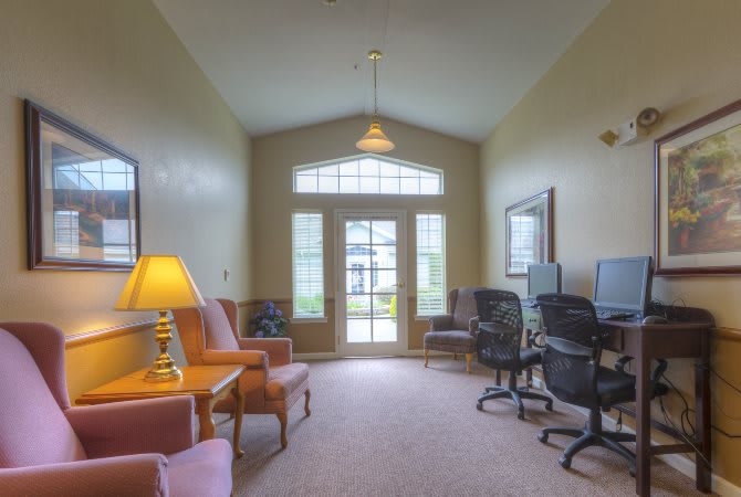 A cozy office space with computers, chairs, and a warm lamp lighting.