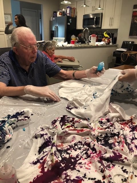 Elderly individuals engaging in a tie-dye art project, enjoying a creative crafting session.