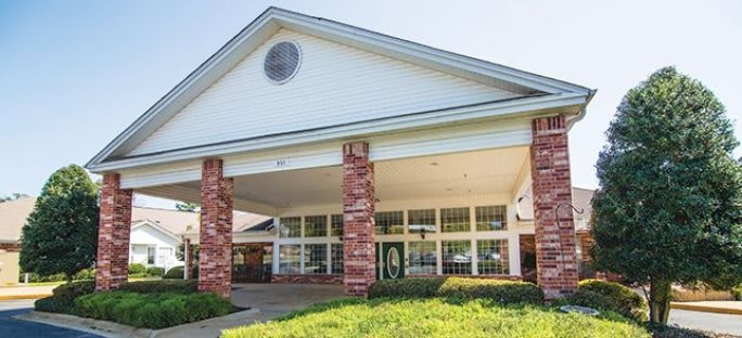 Front view of a building entrance with brick columns and large windows.