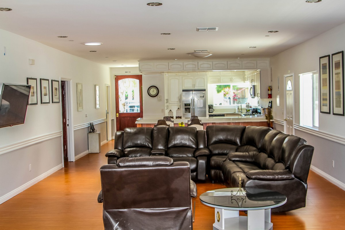 An open-plan living room with a leather sofa set and view into the kitchen.