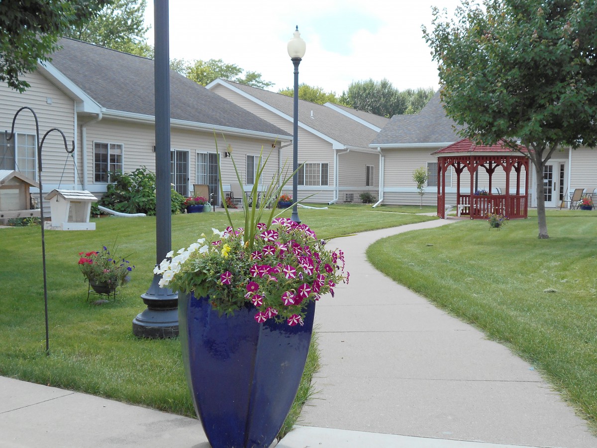 A beautifully landscaped garden area with a pathway, vibrant flowers, and a gazebo in the background.
