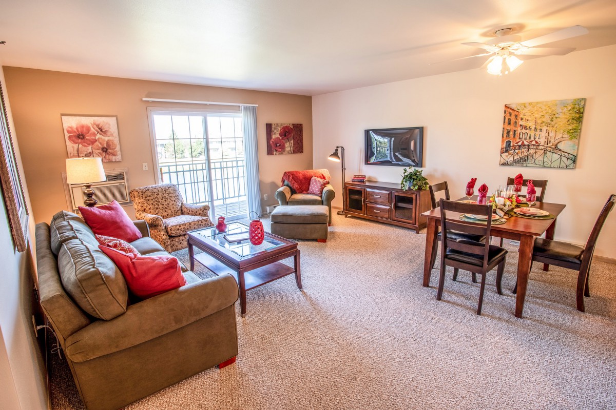 A cozy and well-lit living room featuring a sofa, coffee table, TV, and dining area.