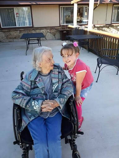 A heartwarming moment shared between a young girl and an elderly woman outdoors.