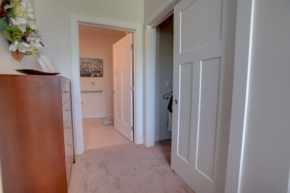 A view of a hallway with doors leading to different rooms. A dresser is visible on the left side.