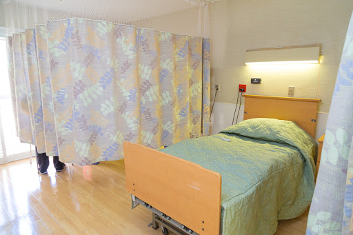 A clean and orderly patient room in a hospital, featuring a bed and privacy curtains.
