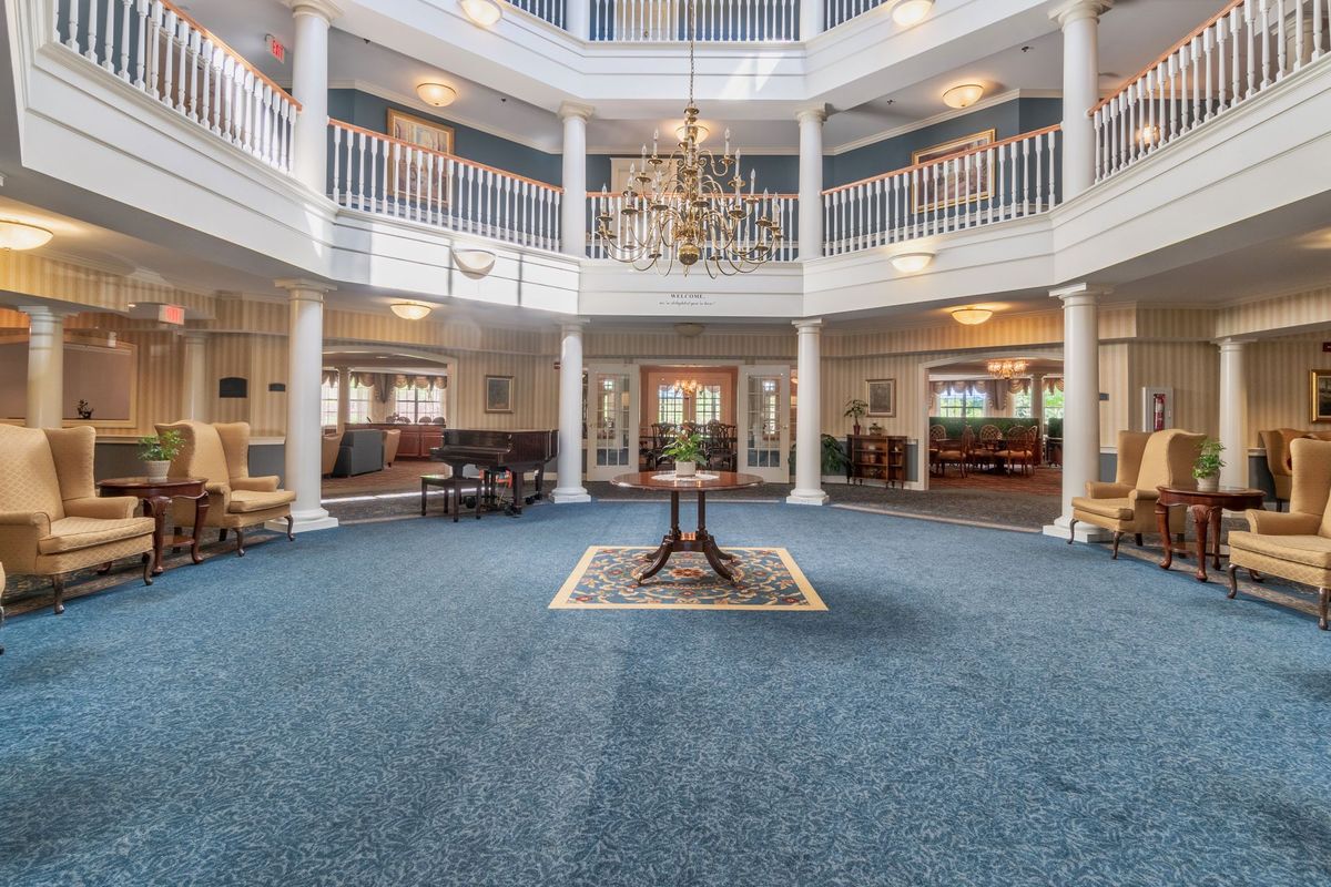 A spacious and elegant lobby with a central chandelier, surrounded by columns and seating areas.