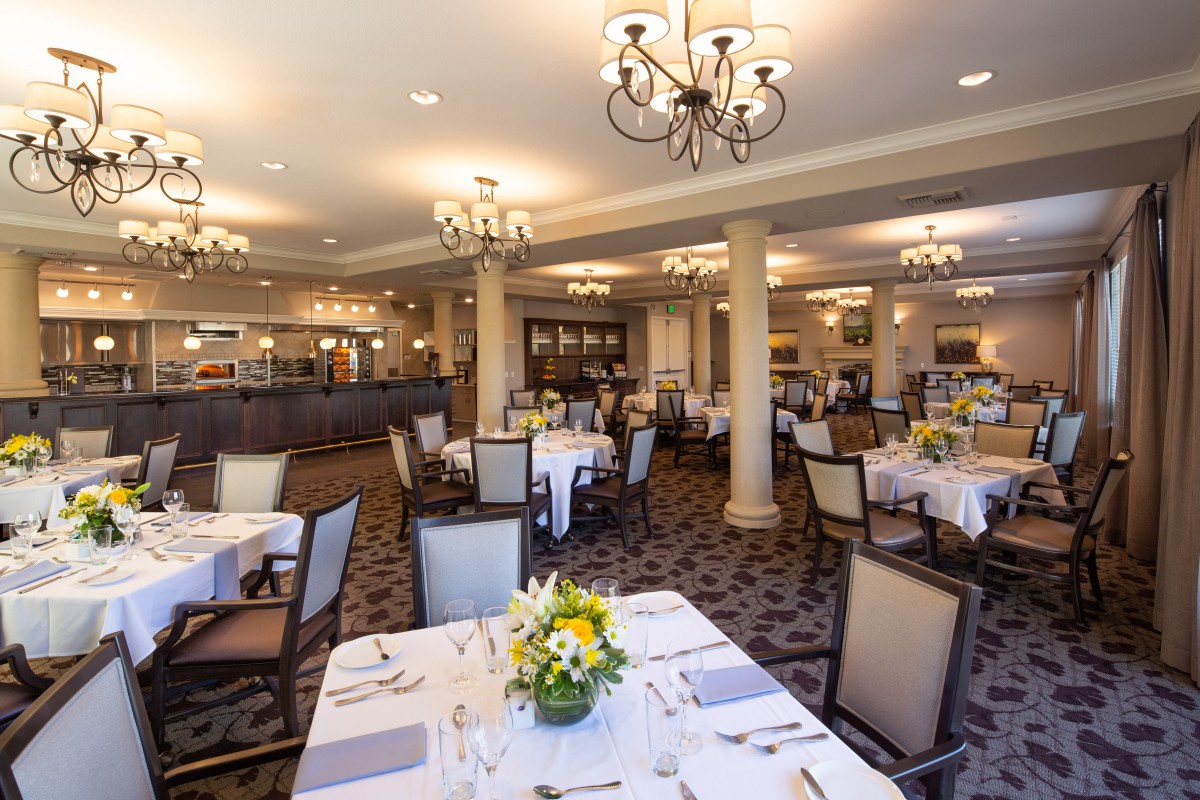 An elegant dining room with set tables and decorative chandeliers.