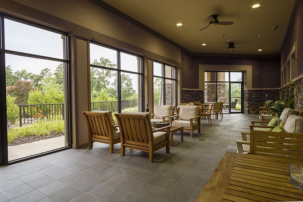 A spacious lounge area with wooden chairs and large windows offering natural light.