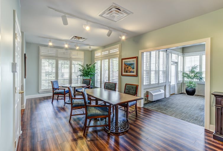 A modern conference room with a wooden table, chairs, and large windows allowing natural light to fill the space.