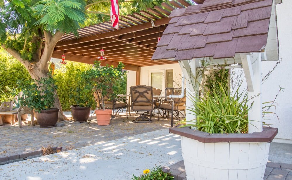A cozy patio area with a pergola, outdoor furniture, and lush greenery.