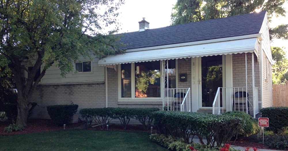 A quaint residential house with a well-kept front yard and an awning over the front window.