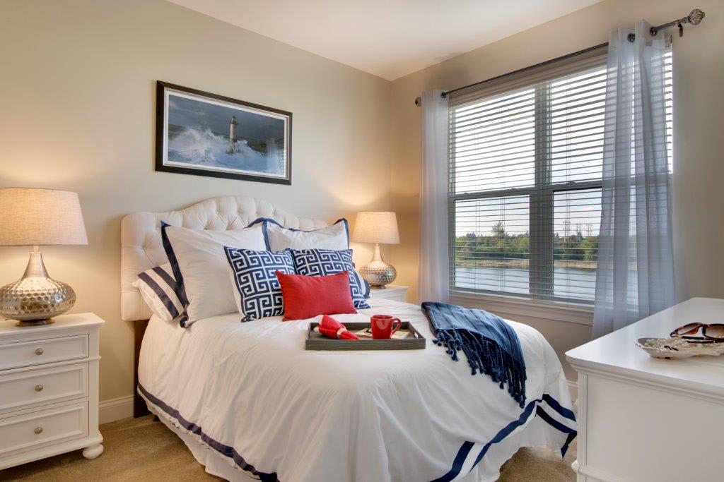 A cozy bedroom with stylish decor and ample natural light from a large window.