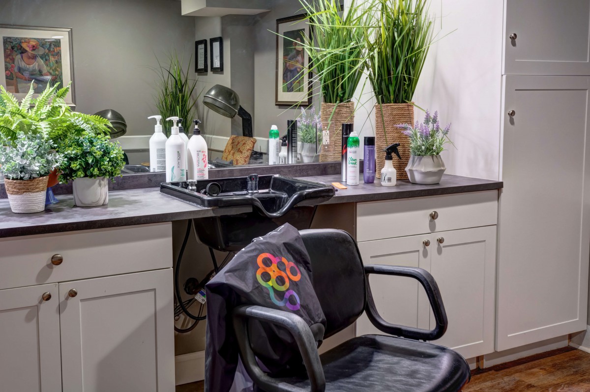 A cozy hair salon station with a styling chair, sink, and various hair products.