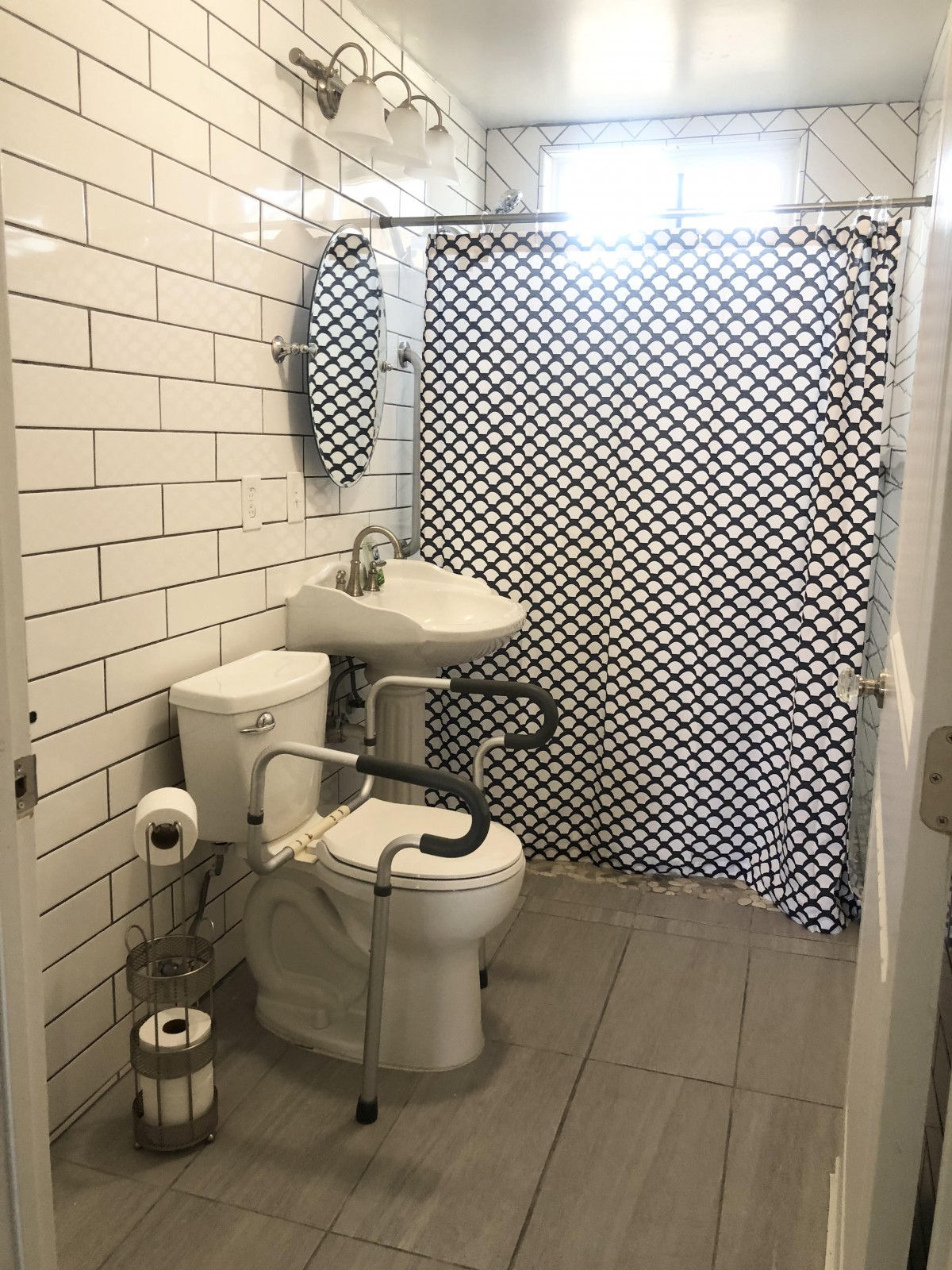 An accessible bathroom with a toilet, sink, and a patterned shower curtain.