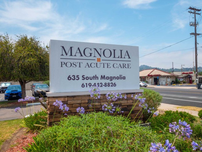 Sign for Magnolia Post Acute Care with surrounding flowers.